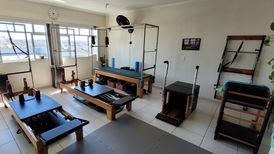 Sala da unidade Planalto: aparelhos de Pilates junto às janelas, com vista para a cidade.