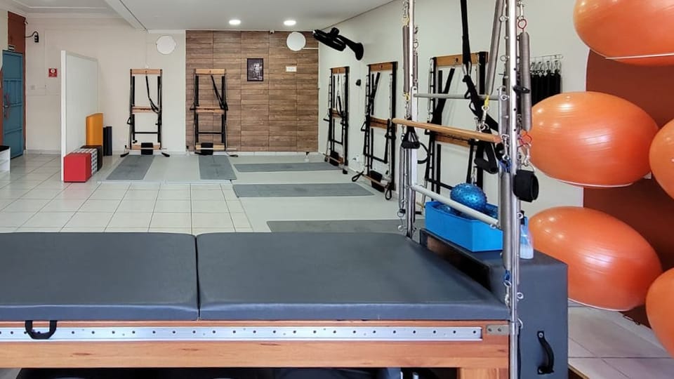 Sala da unidade Santa Terezinha: aparelhos de Pilates, bolas laranja e parede de madeira ao fundo.